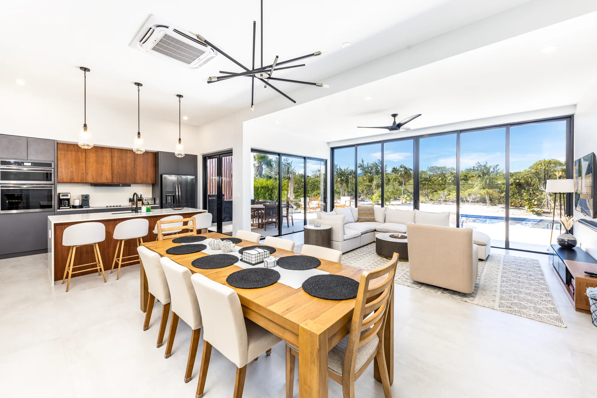 Open-plan dining, living room and kitchen with sliding doors looking toward the pool